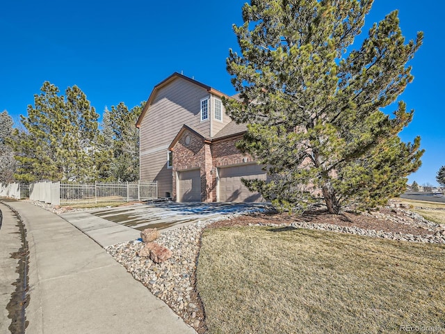 view of property exterior with a garage, brick siding, fence, concrete driveway, and a yard