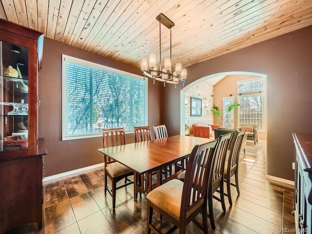 dining area with a chandelier, arched walkways, wood ceiling, and baseboards