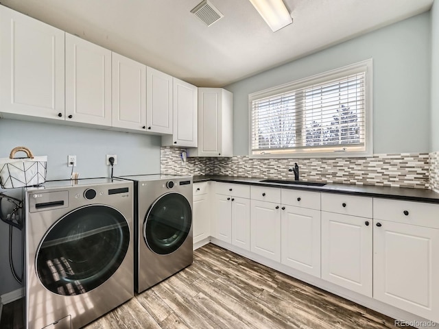 laundry room with washing machine and dryer, dark wood-style flooring, a sink, visible vents, and cabinet space