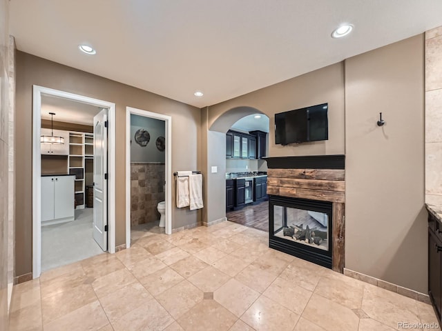 living area featuring arched walkways, a multi sided fireplace, and recessed lighting