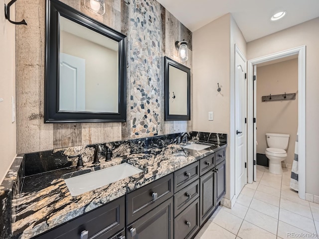 bathroom with double vanity, tile patterned flooring, a sink, and toilet