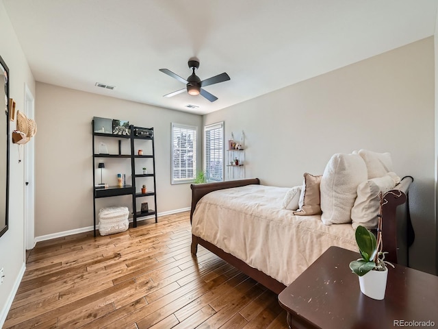 bedroom featuring ceiling fan, wood finished floors, visible vents, and baseboards