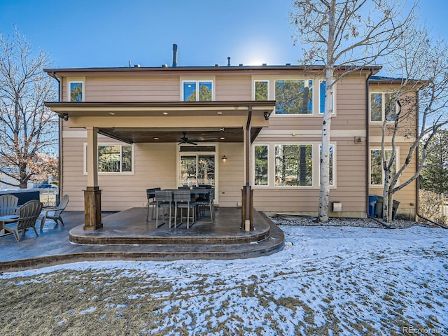 snow covered back of property featuring a ceiling fan and a patio area