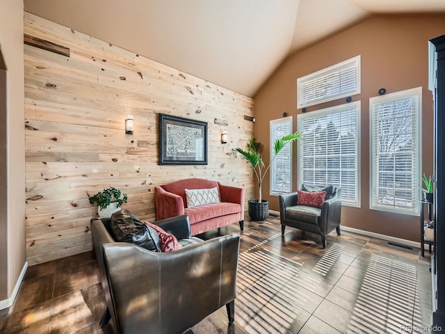 sitting room featuring baseboards, wood walls, lofted ceiling, and visible vents