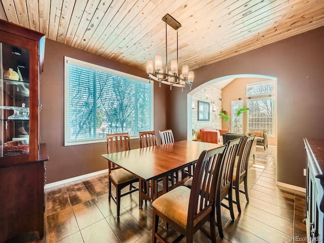 tiled dining space featuring arched walkways, baseboards, an inviting chandelier, and wooden ceiling