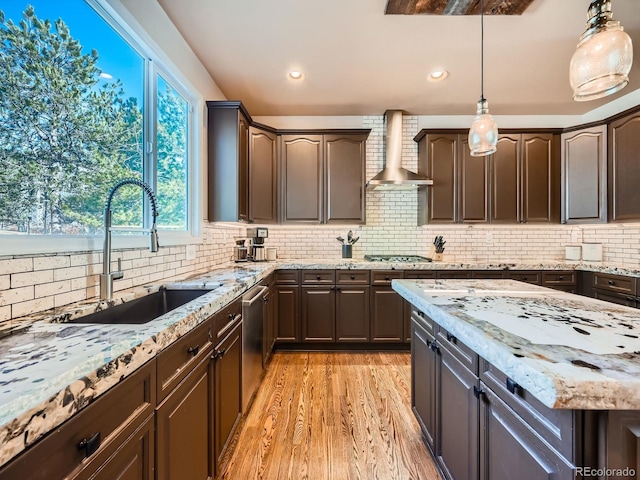 kitchen featuring wall chimney range hood, dark brown cabinetry, backsplash, and light wood-style flooring