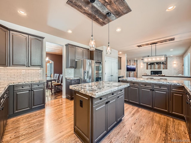 kitchen featuring appliances with stainless steel finishes, decorative backsplash, a kitchen island, and light wood finished floors