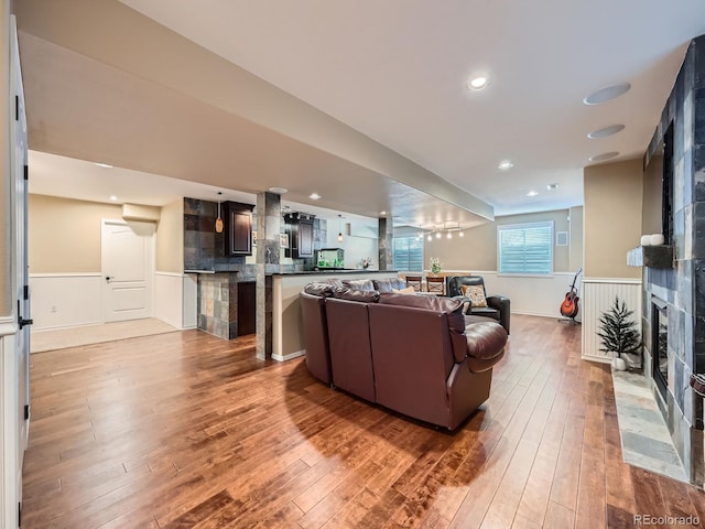 living area with a fireplace, wainscoting, and hardwood / wood-style floors