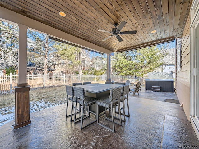view of patio with a fenced backyard, a ceiling fan, a hot tub, and outdoor dry bar