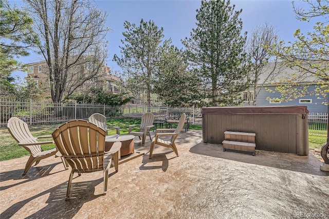 view of patio / terrace with a hot tub, a fenced backyard, and an outdoor fire pit