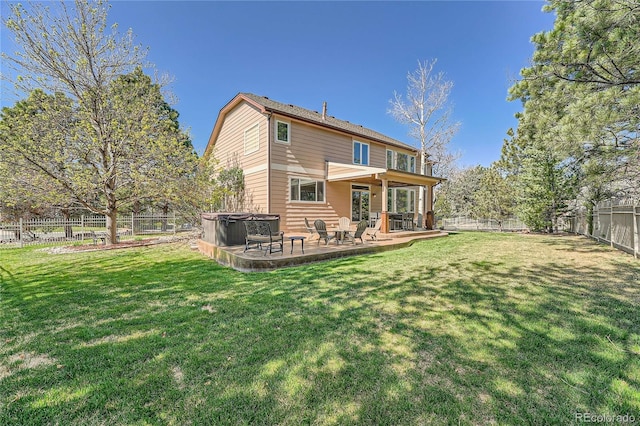 rear view of house featuring a lawn, a fenced backyard, a hot tub, and a patio area