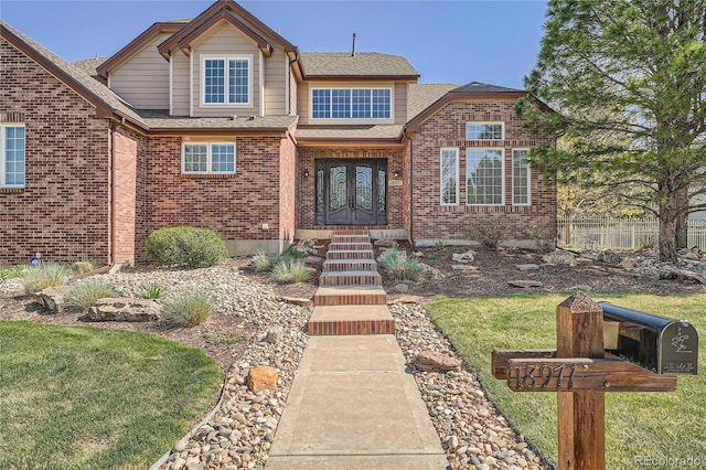 view of front of home with brick siding, a shingled roof, a front lawn, and fence