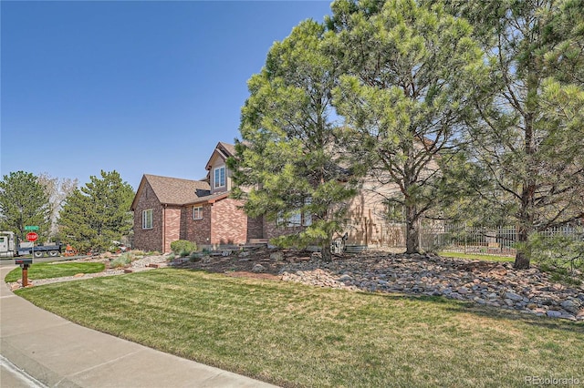 exterior space with brick siding, fence, and a yard