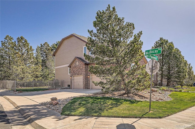 view of front of property featuring fence, brick siding, a garage, a front yard, and concrete driveway