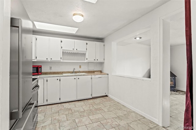 2613 Wren Dr, Colorado Springs, CO 80909 - kitchen featuring white cabinets, a sink, light countertops, stainless steel appliances, and a skylight
