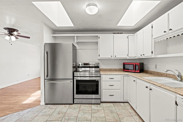2613 Wren Dr, Colorado Springs, CO 80909 - kitchen featuring appliances with stainless steel finishes, light countertops, open shelves, a skylight, and a sink