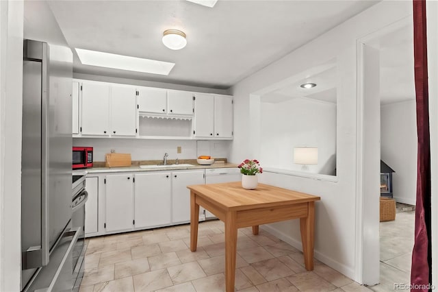 2613 Wren Dr, Colorado Springs, CO 80909 - kitchen with a sink, light countertops, white cabinetry, stainless steel appliances, and a skylight