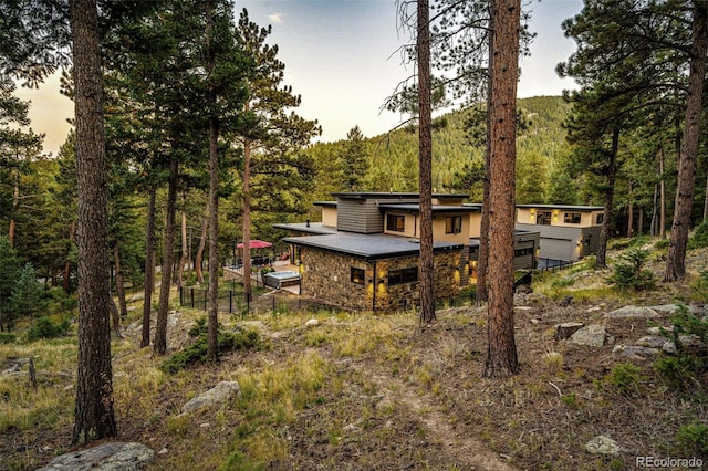 32651 Buffalo Creek Rd, Evergreen, CO 80439 - rear view of property with stone siding and a wooded view