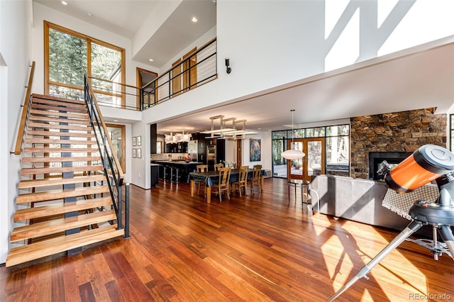 32651 Buffalo Creek Rd, Evergreen, CO 80439 - living area with a stone fireplace, stairway, wood finished floors, and a towering ceiling