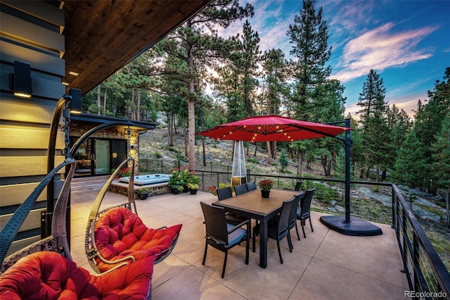 32651 Buffalo Creek Rd, Evergreen, CO 80439 - patio terrace at dusk with a hot tub, a patio area, outdoor dining space, and view of scattered trees