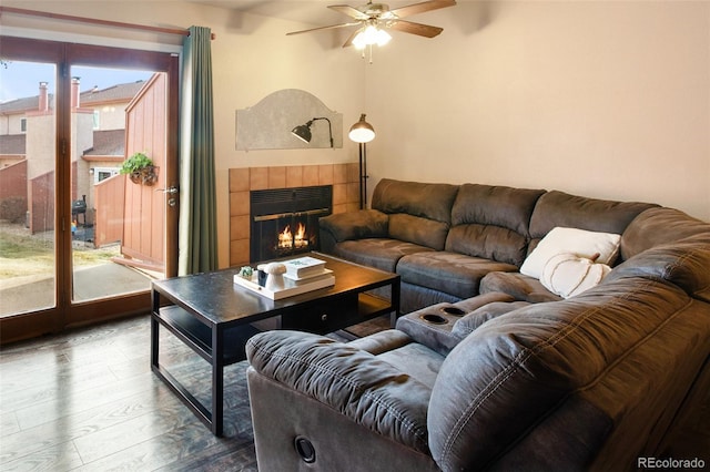 living room with ceiling fan, dark wood-type flooring, and a tile fireplace