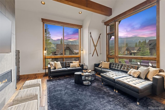 living room with a tile fireplace, a mountain view, lofted ceiling with beams, and hardwood / wood-style flooring