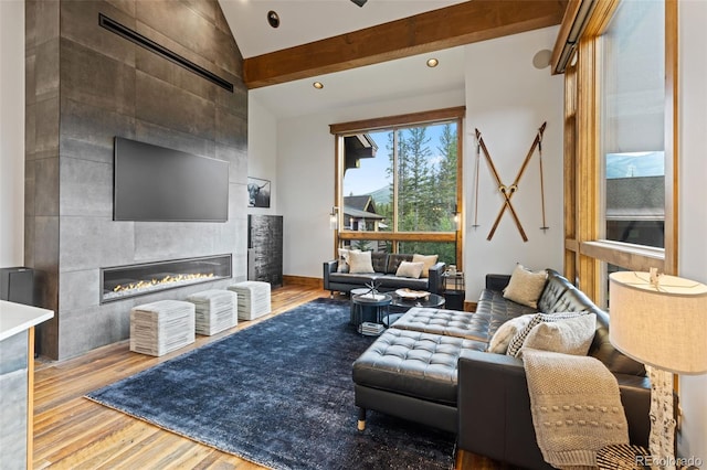 living room featuring a tile fireplace, vaulted ceiling, and light hardwood / wood-style flooring