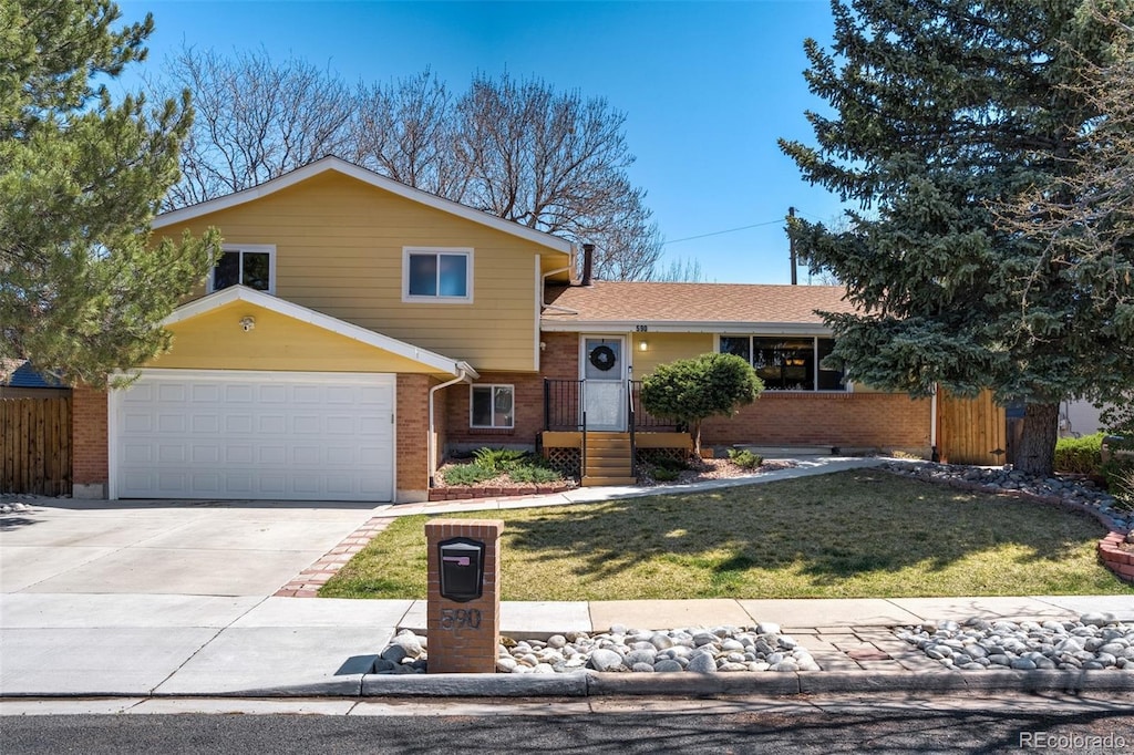 590 S Troy St, Aurora, CO 80012 - split level home featuring concrete driveway, a front lawn, an attached garage, fence, and brick siding