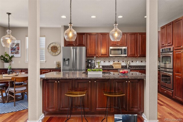24702 E Ontario Dr, Aurora, CO 80016 - kitchen featuring appliances with stainless steel finishes, light wood-style flooring, tasteful backsplash, recessed lighting, and pendant lighting