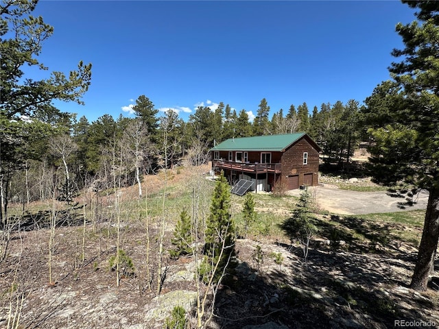 72 Rudi Ln W, Golden, CO 80403 - view of yard with concrete driveway, an attached garage, a deck, and view of wooded area