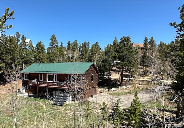 72 Rudi Ln W, Golden, CO 80403 - rear view of house featuring driveway, a wooden deck, a garage, a metal roof, and solar panels