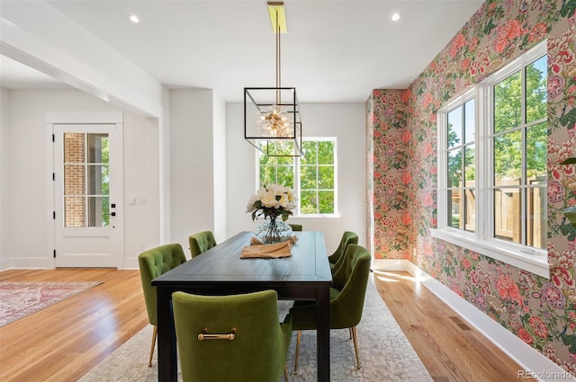 dining area with light hardwood / wood-style floors, an inviting chandelier, and a wealth of natural light