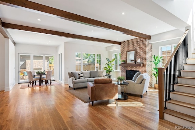 living room featuring a fireplace, light hardwood / wood-style flooring, beamed ceiling, and a wealth of natural light