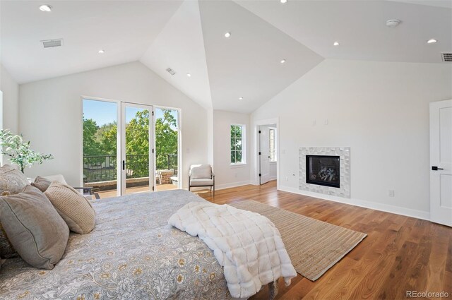 bedroom with high vaulted ceiling, light wood-type flooring, access to exterior, and a fireplace