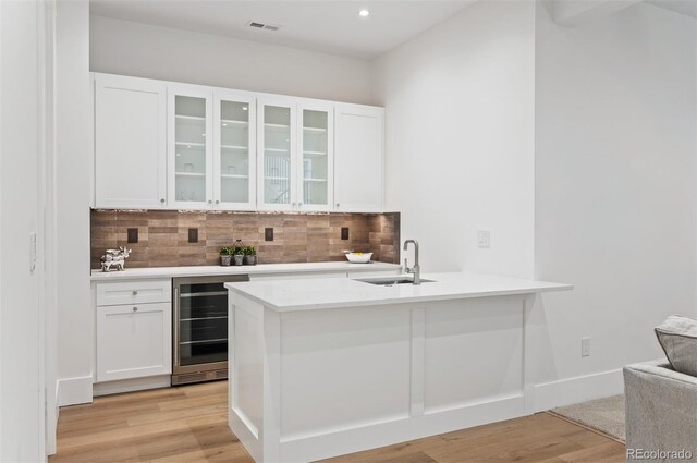 kitchen with white cabinets, wine cooler, and sink