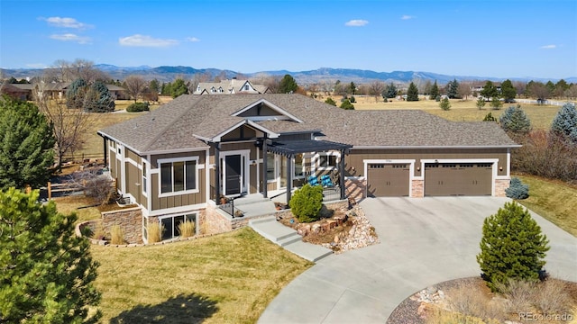 view of front of property with board and batten siding, a front lawn, a mountain view, stone siding, and an attached garage