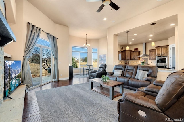 living area featuring dark wood finished floors, recessed lighting, ceiling fan with notable chandelier, and baseboards