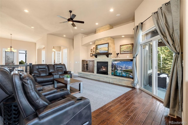 living area featuring a wealth of natural light, arched walkways, dark wood-style floors, and ceiling fan with notable chandelier