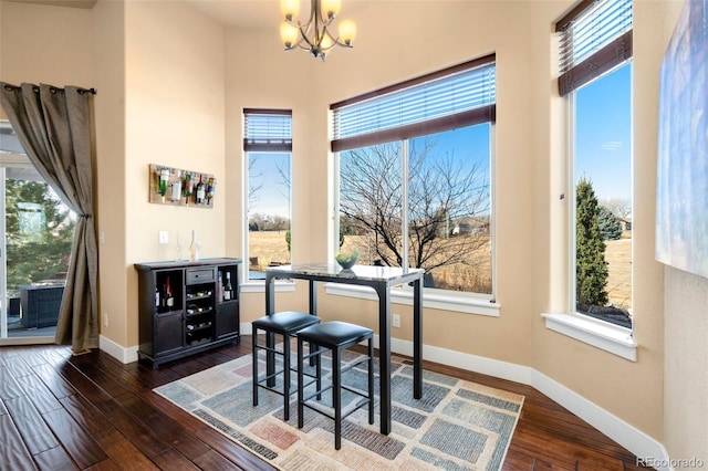 dining area with dark wood finished floors, baseboards, a wealth of natural light, and an inviting chandelier