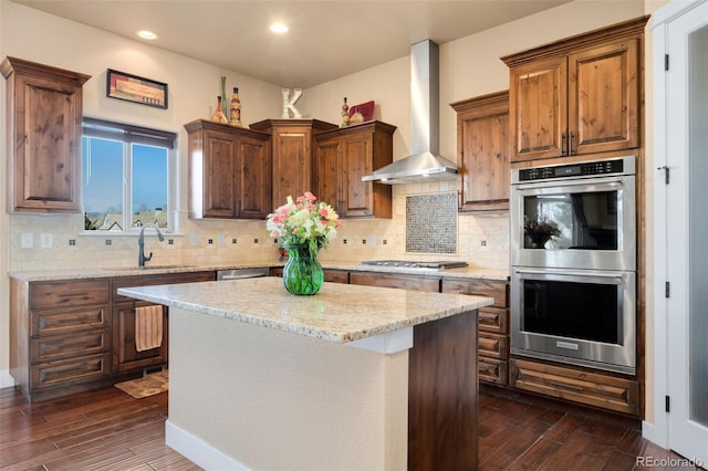 kitchen with dark wood-style floors, backsplash, appliances with stainless steel finishes, and wall chimney exhaust hood