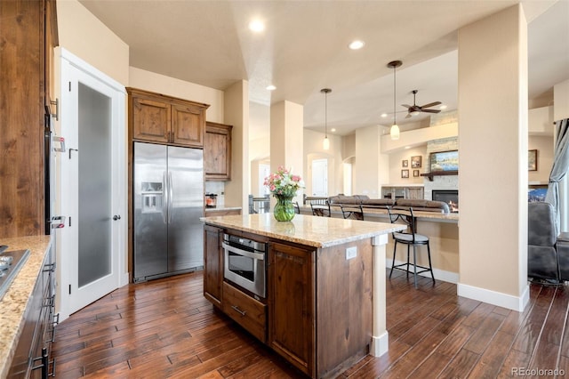 kitchen featuring a breakfast bar, dark wood-style flooring, appliances with stainless steel finishes, and ceiling fan