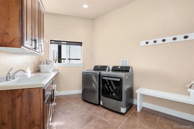 washroom featuring a sink, washer and dryer, cabinet space, light tile patterned floors, and baseboards