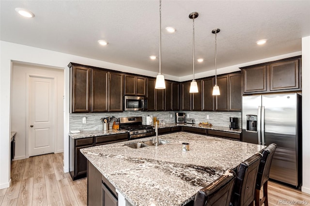 960 S De Gaulle Ct, Aurora, CO 80018 - kitchen with appliances with stainless steel finishes, dark brown cabinetry, light wood finished floors, light stone countertops, and recessed lighting