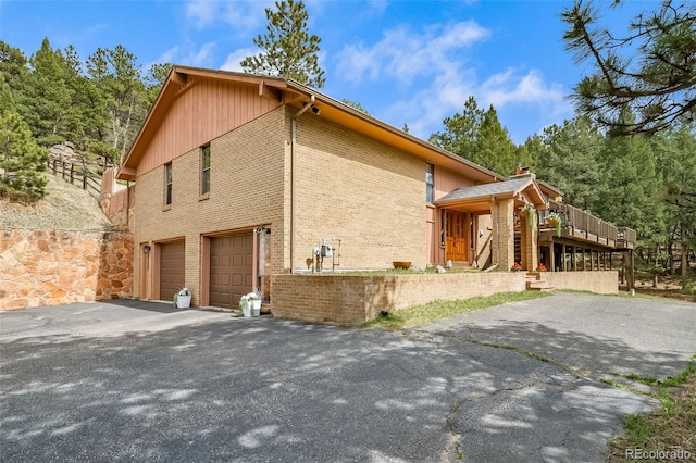 7815 Armadillo Trl, Evergreen, CO 80439 - view of property exterior featuring an attached garage, aphalt driveway, and brick siding