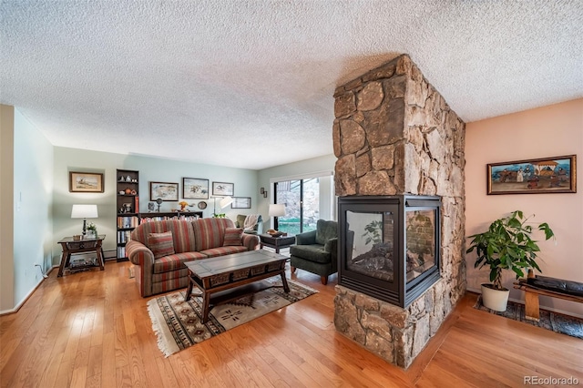 7815 Armadillo Trl, Evergreen, CO 80439 - living room featuring a stone fireplace, a textured ceiling, baseboard heating, and hardwood / wood-style floors