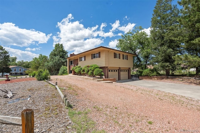 1244 Baron Rd, Colorado Springs, CO 80918 - view of front of property featuring asphalt driveway, brick siding, an attached garage, and a chimney
