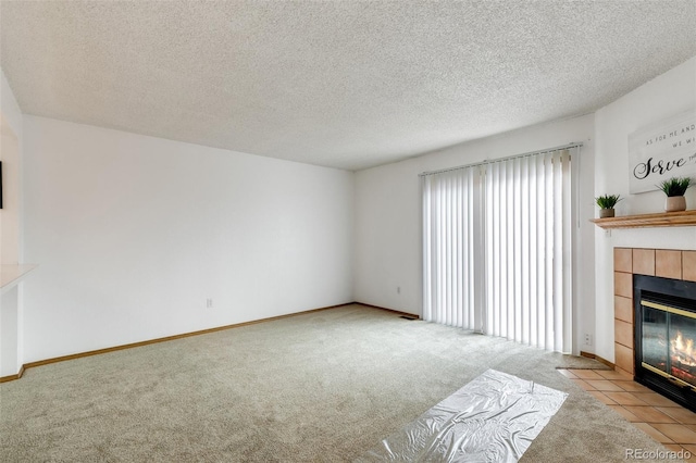 unfurnished living room featuring a tiled fireplace, light carpet, and a textured ceiling