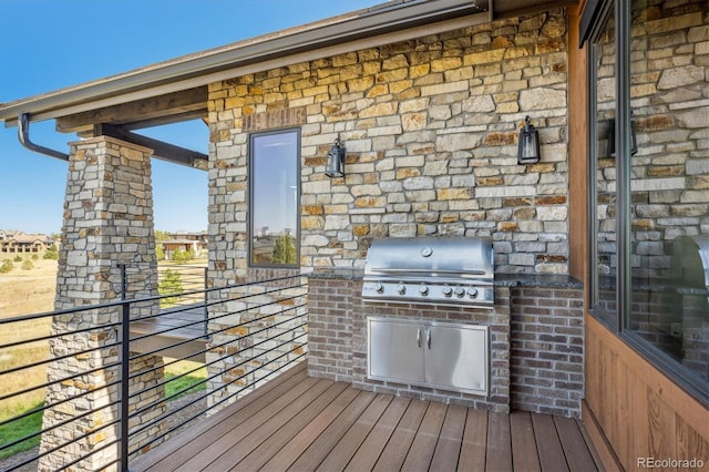 wooden deck featuring grilling area and an outdoor kitchen