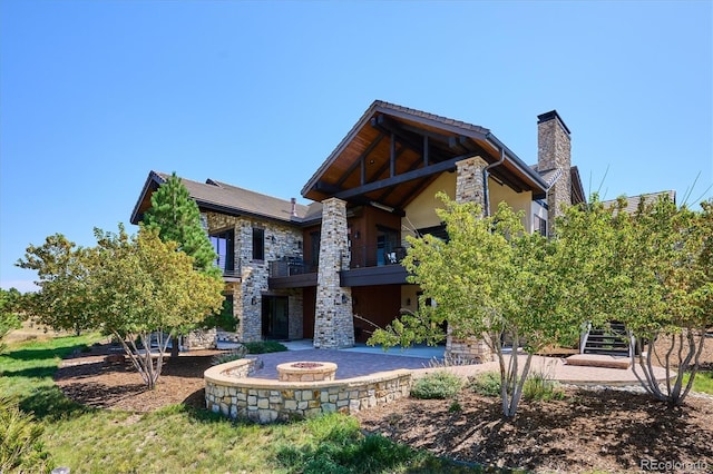 rear view of property featuring a fire pit and a patio