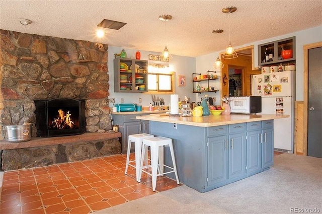 kitchen featuring a fireplace, white appliances, a kitchen bar, and a textured ceiling